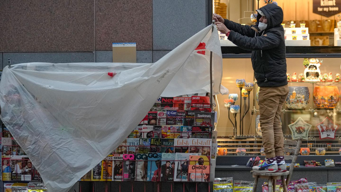 Wien, Österreich. Ein Verkäufer deckt einen Kiosk in einer Einkaufsstraße mit einer Plastikfolie ab.