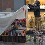 Wien, Österreich. Ein Verkäufer deckt einen Kiosk in einer Einkaufsstraße mit einer Plastikfolie ab.