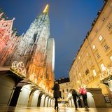 Wien, Österreich. Passanten gehen am Stephansdom und dem geschlossenen Weihnachtsmarkt vorbei.