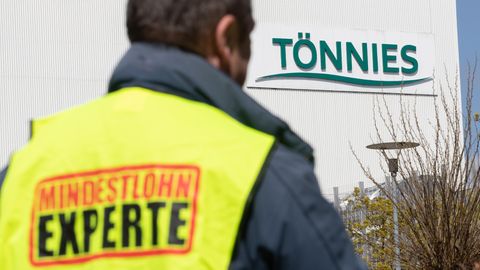 Mindestlohn Experte steht auf einer Weste, die ein Gewerkschaftsvertreter vor dem Tönnies-Werk trägt