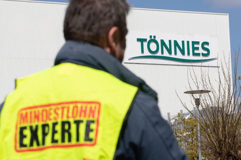Mindestlohn Experte steht auf einer Weste, die ein Gewerkschaftsvertreter vor dem Tönnies-Werk trägt