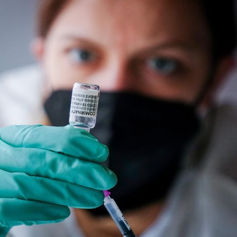 Eine Mitarbeiterin schaut genau hin, als sie eine Impfspritze aufzieht