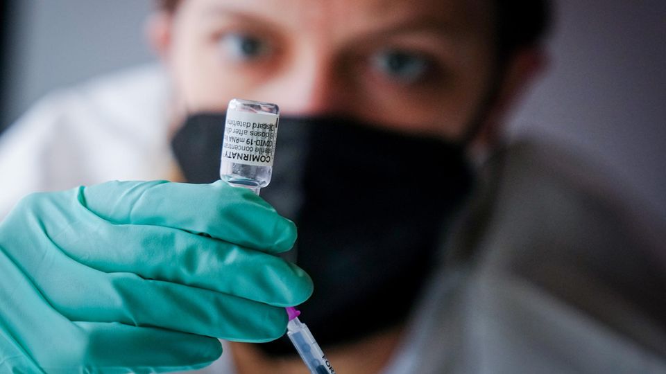 Eine Mitarbeiterin schaut genau hin, als sie eine Impfspritze aufzieht