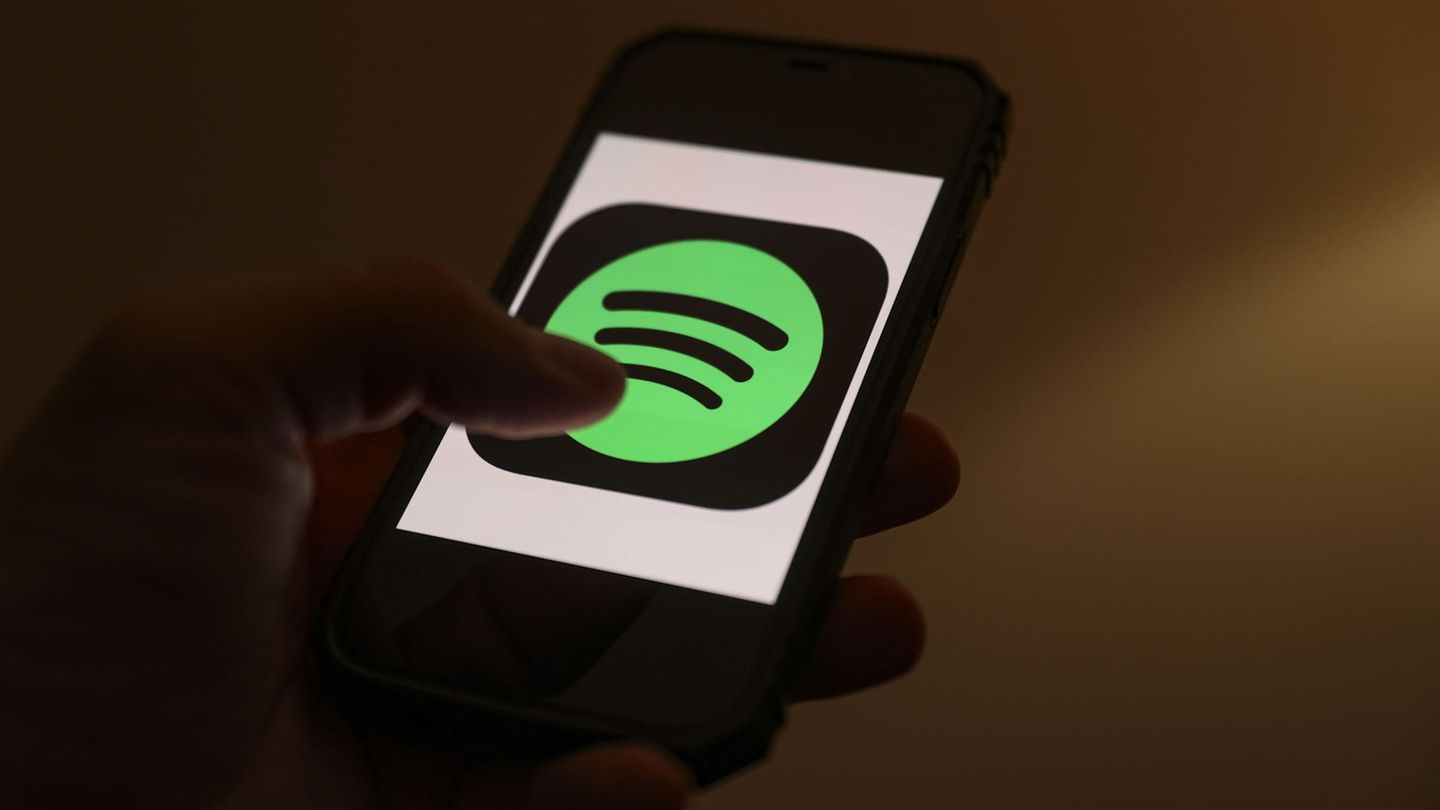 One person operating a smartphone that opens a Spotify streaming app