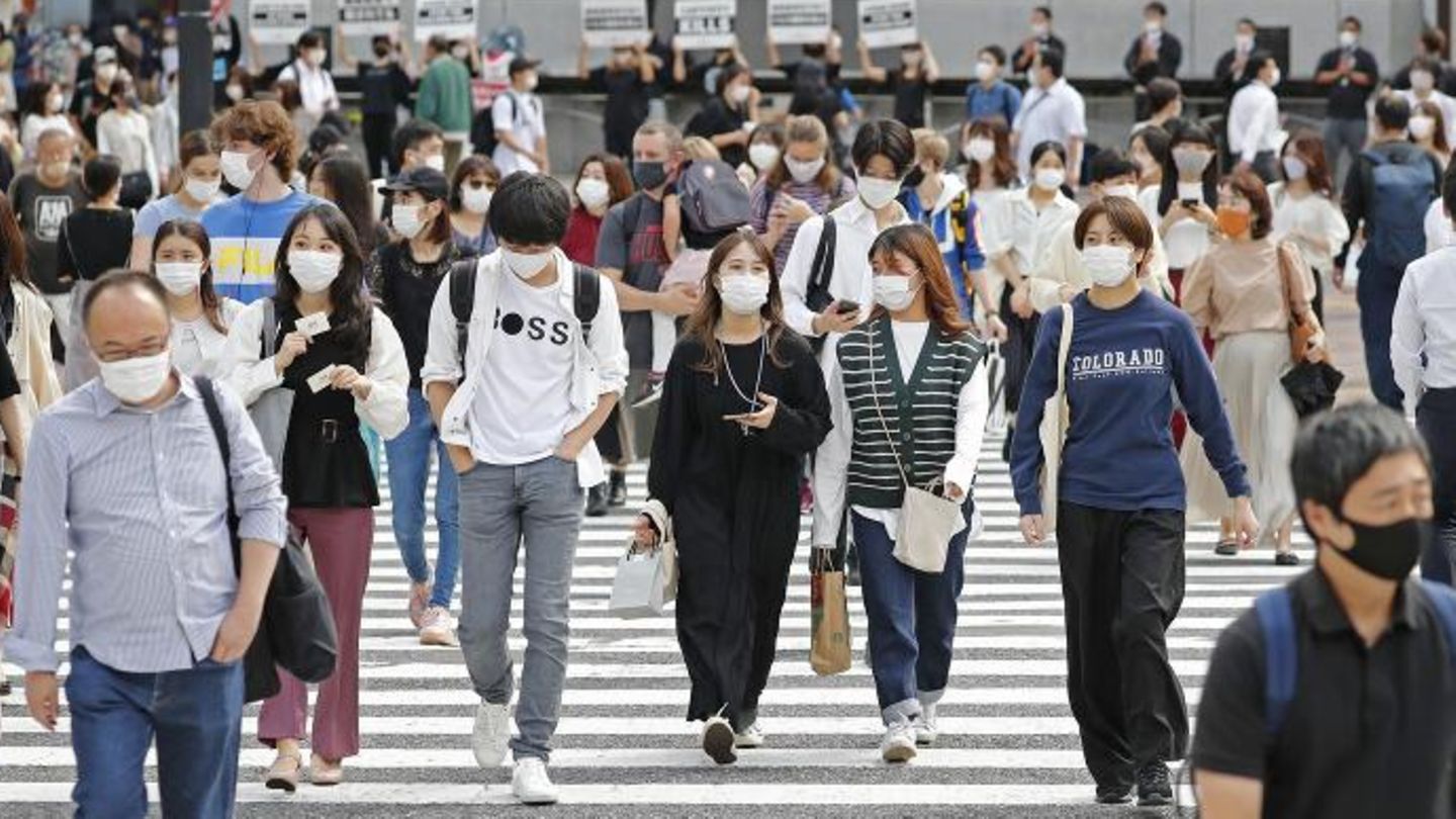 Menschen mit Maske gehen in Japan über Straße