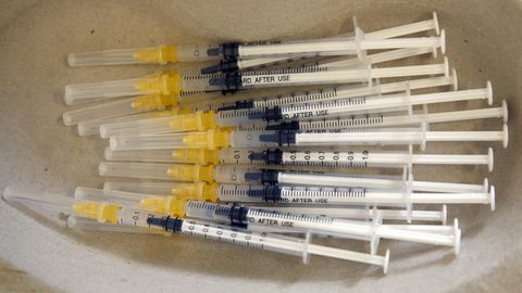 Spritzen mit Impfserum liegen in einer Schale bereit.