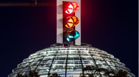 Eine Ampel vor der Kuppel des Reichstagsgebäudes leuchtet in einer Langzeitbelichtung in allen drei Phasen