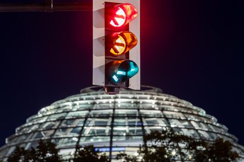 Eine Ampel vor der Kuppel des Reichstagsgebäudes leuchtet in einer Langzeitbelichtung in allen drei Phasen