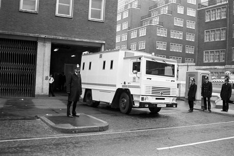 Ein weißer Transporter auf eine Schwarzweiß-Foto, im Vordergrund ist ein englischer Polizist zu sehen