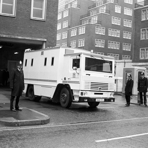 Ein weißer Transporter auf eine Schwarzweiß-Foto, im Vordergrund ist ein englischer Polizist zu sehen
