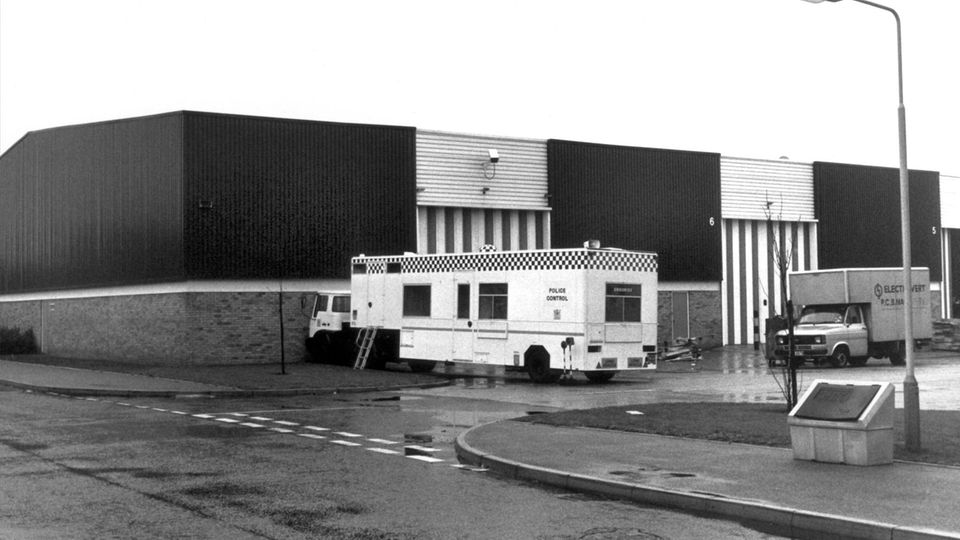 Ein Schwarzweißfoto zeigt eine dunkle Lagerhalle und einen weißen Transporter