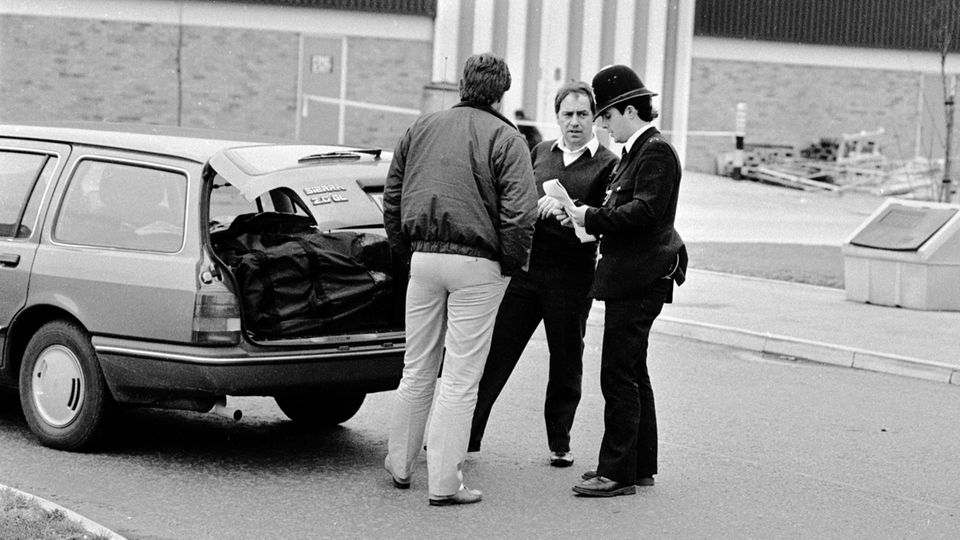 Ein Schwarzweißfoto zeigt einen Polizisten, der Autofahrer kontrolliert
