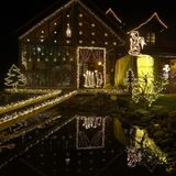 usgesägte Krippenfiguren, mit Lichtern umrahmt, leuchten im Garten eines sogenannten Weihnachtshauses