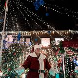 Dirk van Acken steht als Weihnachtsmann verkleidet in seinem Garten, der mit vielen Lichtern weihnachtlich dekoriert ist