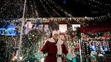Dirk van Acken steht als Weihnachtsmann verkleidet in seinem Garten, der mit vielen Lichtern weihnachtlich dekoriert ist