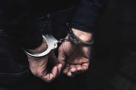 Zwei Hände hinterm Rücken in Handschellen