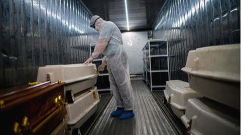 Südafrika, Johannesburg: Ein Angestellter einer Leichenhalle trägt Schutzkleidung und überprüft in einem Kühlcontainer Särge mit Corona-Opfern. Die Ausbreitung einer neuen möglicherweise sehr gefährlichen Variante des Coronavirus' im südlichen Afrika hat international Besorgnis ausgelöst. 