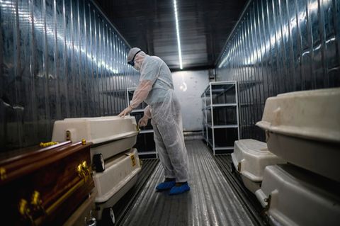 Südafrika, Johannesburg: Ein Angestellter einer Leichenhalle trägt Schutzkleidung und überprüft in einem Kühlcontainer Särge mit Corona-Opfern. Die Ausbreitung einer neuen möglicherweise sehr gefährlichen Variante des Coronavirus' im südlichen Afrika hat international Besorgnis ausgelöst. 