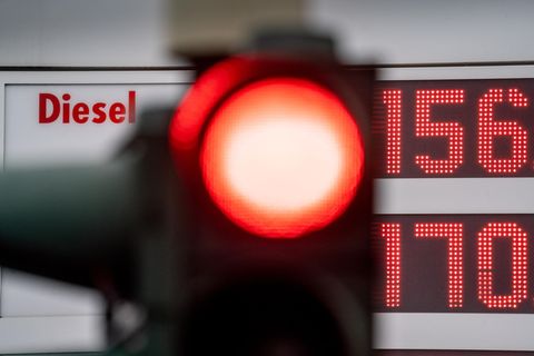 Eine rote Ampel leuchtet vor der Preistafel einer Tankstelle
