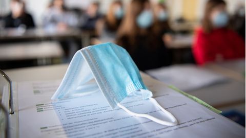 Eine Atemschutzmasken liegt auf einem Tisch in einem Klassenzimmer