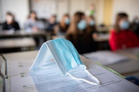 Eine Atemschutzmasken liegt auf einem Tisch in einem Klassenzimmer