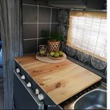 Die dunkle Farbe und die helle Holzabdeckung heben die Küche heraus.