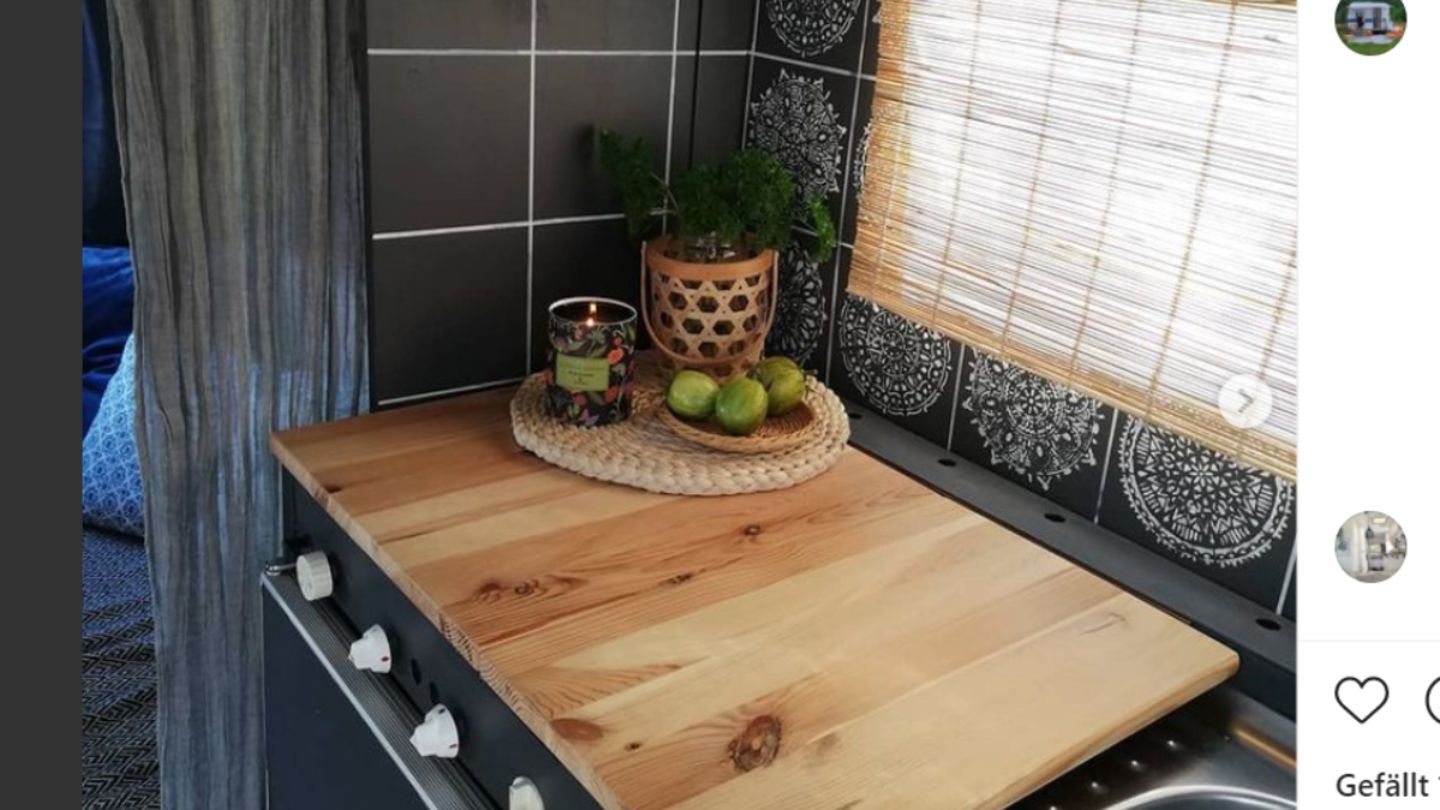 Die dunkle Farbe und die helle Holzabdeckung heben die Küche heraus.