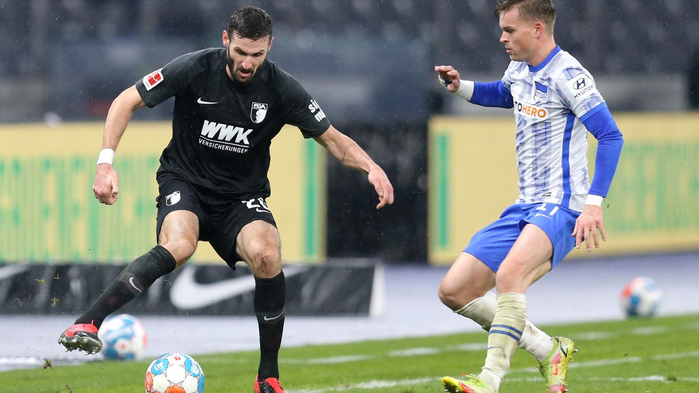 Im Berliner Olympiastadion nutzte der ehemalige Augsburger Marco Richter (40.) einen Patzer seines früheren Mitspielers Robert Gumny und schoss zum 1:0 ein. Die Augsburger mussten kurzfristig auf ihren Kapitän und Innenverteidiger Jeffrey Gouweleeuw verzichten. Der 30 Jahre alte Niederländer sei unmittelbar nach Bekanntwerden eines Corona-Falls im direkten familiären Umfeld "als Vorsichtsmaßnahme von der Mannschaft isoliert worden", wie die Augsburger mitteilten. Michael Gregoritsch belohnte den Kampf der Gäste mit dem Treffer zum 1:1 in der siebten Minute der Nachspielzeit. Hier sind Augsburgs Daniel Caligiuri und Maximilian Mittelstaedt im Zweikampf.