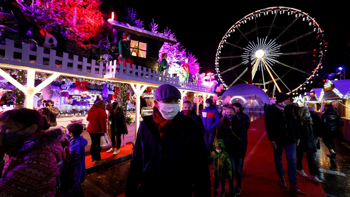 Belgien, Brüssel: Menschen tragen während eines Besuchs des Winterwunders und des Weihnachtsmarkts eine Mund-Nasen-Bedeckung