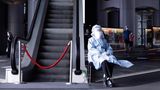 China, Hongkong: Eine Pflegemitarbeiterin in Schutzkleidung sitzt neben einer Rolltreppe