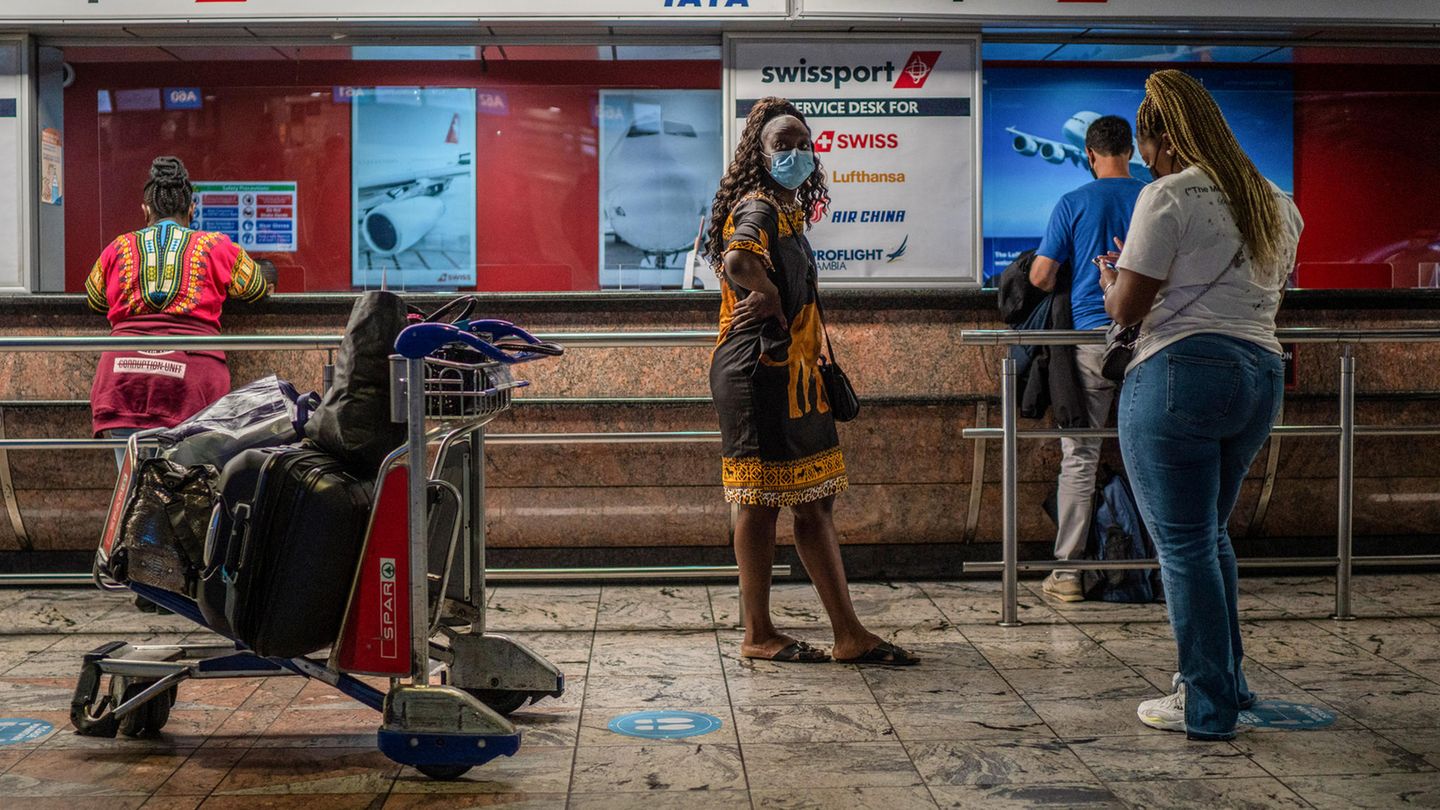 Omikron Südafrika Symptome: Passagiere warten an einem Ticketschalter auf dem O.R. Tambo Flughafen in Johannesburg