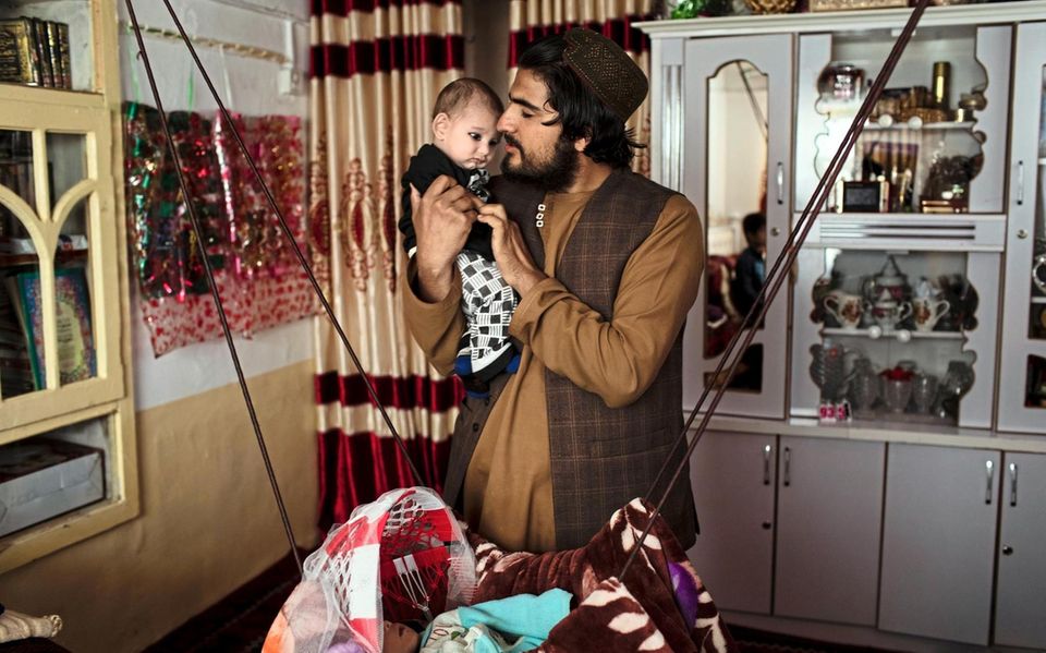 Vaterstolz: Aziz ur-Rahman und seine jüngste Tochter in seinem Wohnzimmer. Seit Kurzem muss er in der lokalen Verwaltung arbeiten. Lieber wäre er Lehrer geblieben