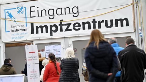 Menschen stehen in Rosenheim vor einem Impfzentrum