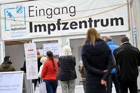 Menschen stehen in Rosenheim vor einem Impfzentrum