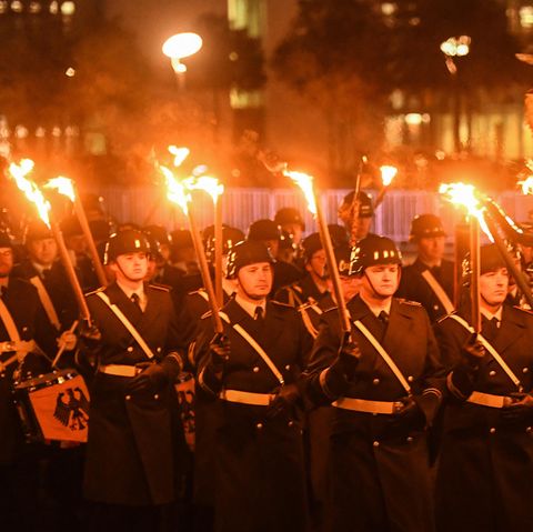 Soldaten in Uniformen stehen mit Fackeln in der Dunkelheit