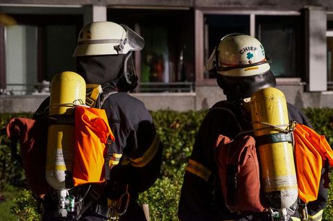 Zwei Feuerwehrleute schauen aud ein Haus