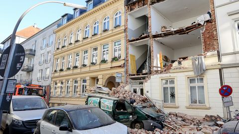 Trümmer liegen auf einem Auto vor einem Haus, dessen Fassade eingestürzt ist