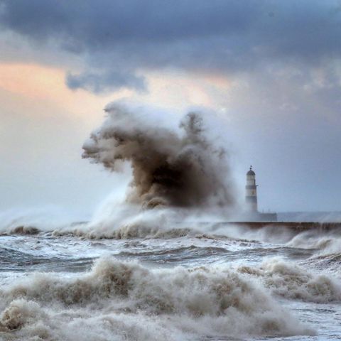 Hohe Wellen schlagen über einen Wellenbrecher vor dem Leuchtturm von Seaham in der Grafschaft County Durham
