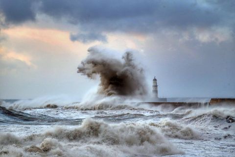 Hohe Wellen schlagen über einen Wellenbrecher vor dem Leuchtturm von Seaham in der Grafschaft County Durham