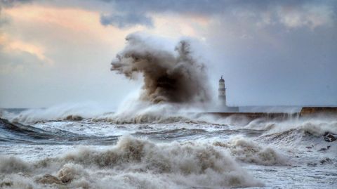 Hohe Wellen schlagen über einen Wellenbrecher vor dem Leuchtturm von Seaham in der Grafschaft County Durham