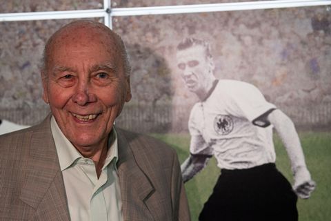 Horst Eckel im Jahr 2019 bei einer Ausstellung neben einem Bild aus seiner aktiven Zeit