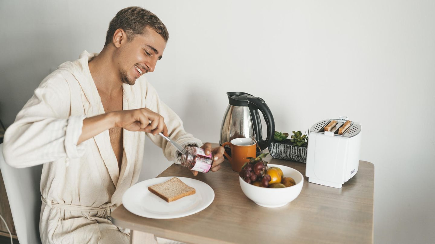 Ein junger Mann isst Toast zum Frühstück