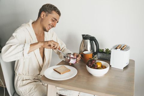 Ein junger Mann isst Toast zum Frühstück