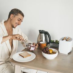 Ein junger Mann isst Toast zum Frühstück