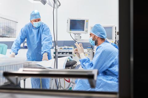 Zwei Chirurgen sitzen erschöpft in einem OP-Saal
