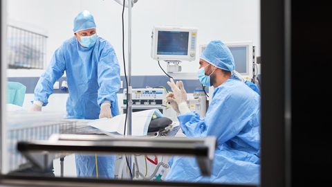 Zwei Chirurgen sitzen erschöpft in einem OP-Saal
