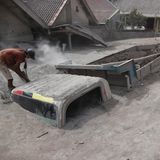 Ein Mann legt mit einer Schaufel das Fesnter eines Lasters frei, der unter Asche begraben wurde