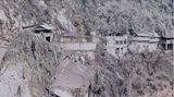 Asche hüllt die Häuser und die Landschaft auf der anderen Seite der Schlucht in ein gespenstisches Grau