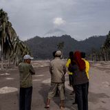 Bange Blicke: Dorfbewohner beobachten aus der Ferne den Semeru, über dessen Gipfel noch immer eine Rauchsäule steht