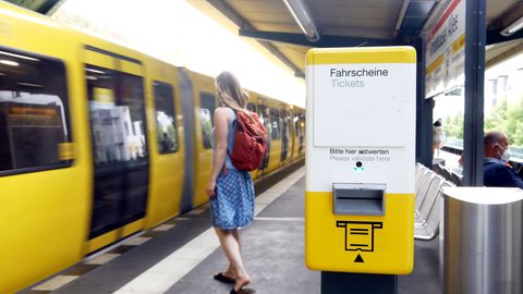 Ein Automat zum Ticketllösen steht an einem Bahnsteig, an dem eine Bahn einfährt
